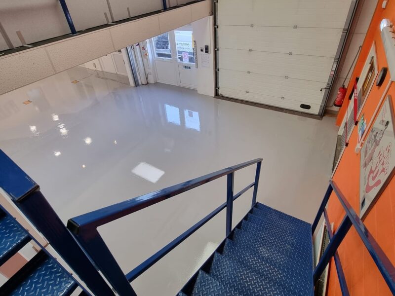Blue stairs descending into warehouse with epoxy flooring
